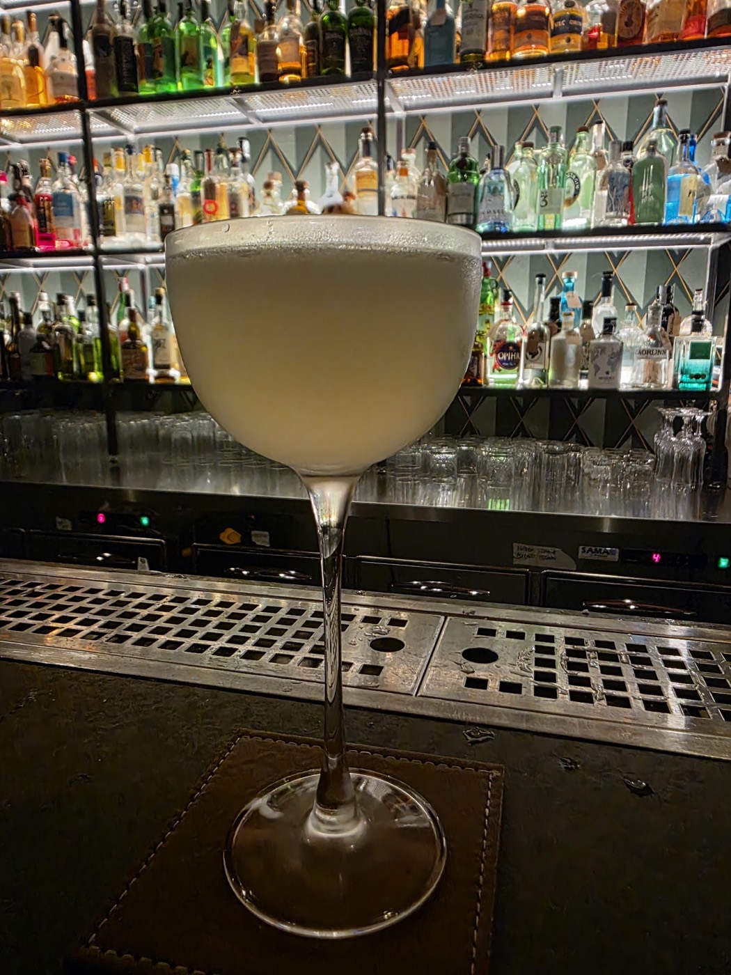 Cocktail in coppa davanti alla bottigliera
