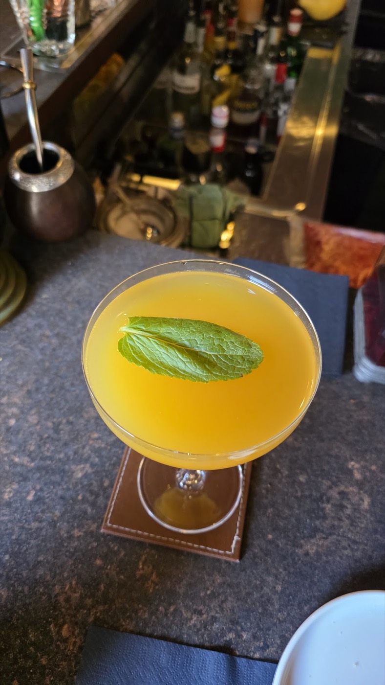 Cocktail giallo con foglia di basilico