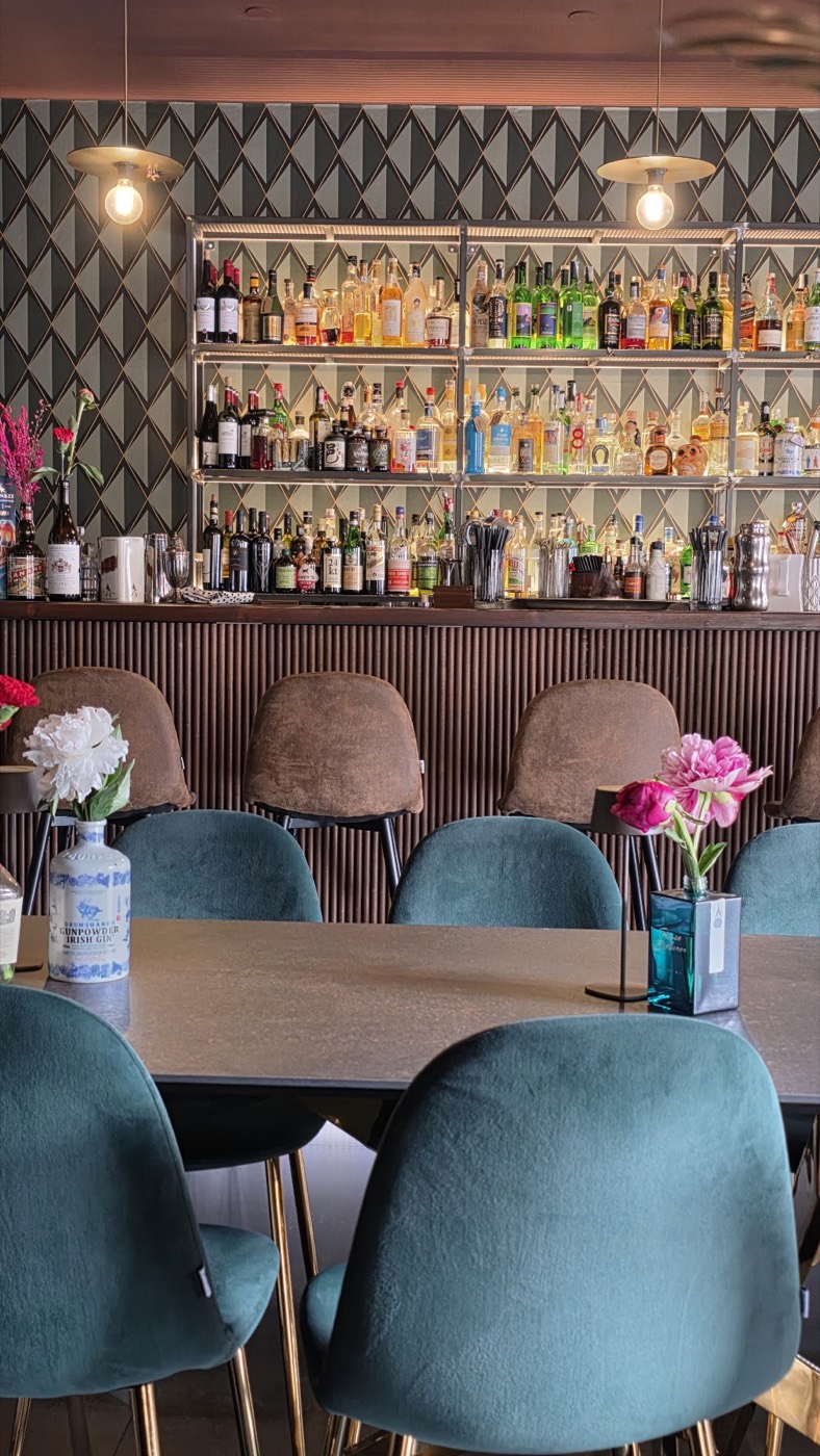 La sala con le poltroncine in velluto verde e i fiori sui tavoli